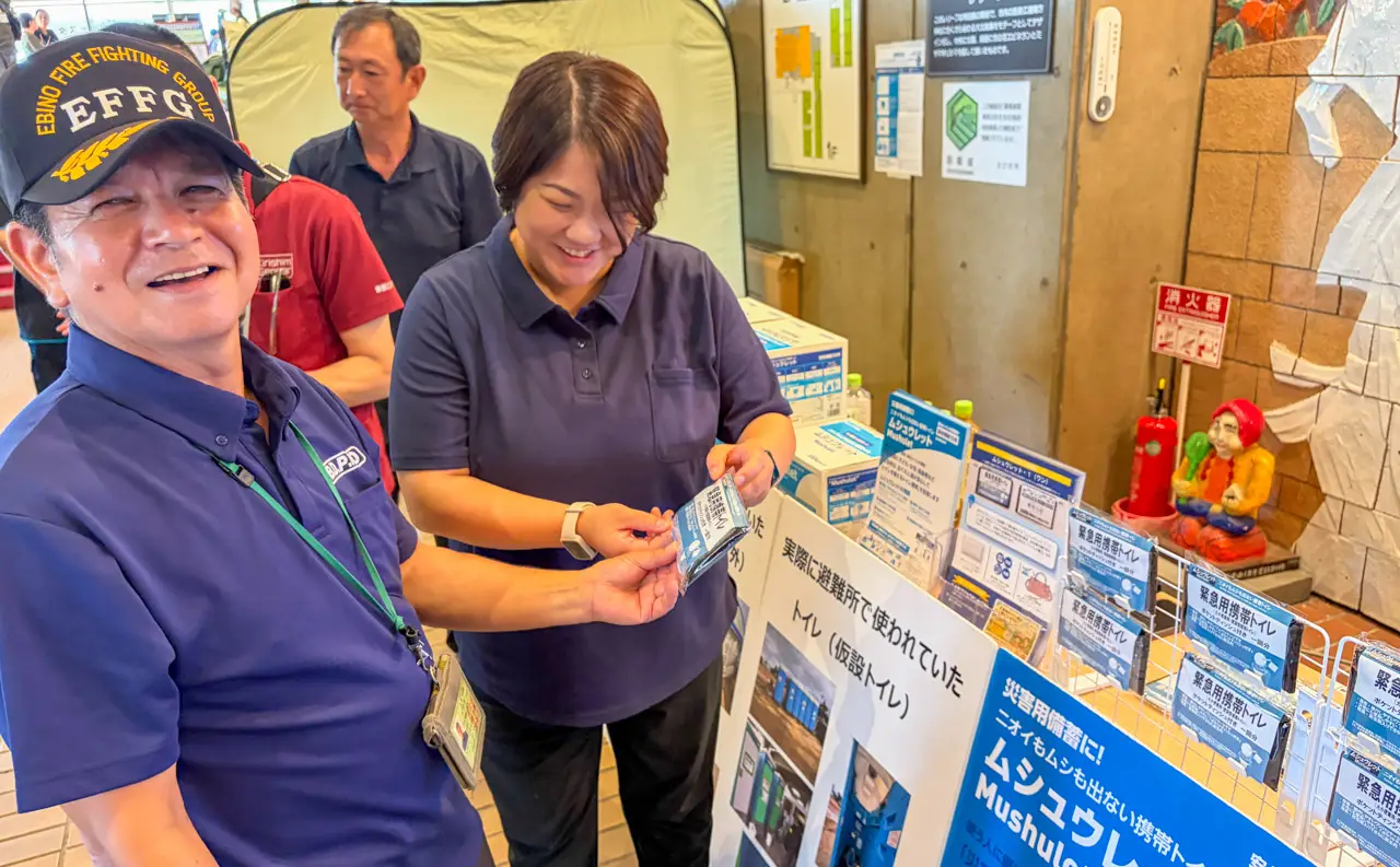 えびの市の担当者に、緊急用携帯トイレ「ムシュウレット・1（ワン）」の特徴や使用方法を紹介する無臭元スタッフ
